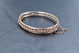 A 9ct gold bracelet, of hinged oval form with twisted decoration, marked 9ct, 10.5grams, 7cm, some