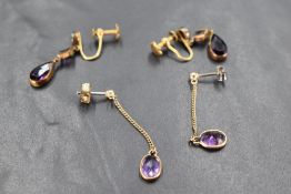 A pair of yellow metal stud earrings having chain drops to amethyst style stones in collared mounts,