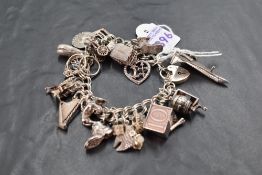 A silver charm bracelet with twenty silver charms including concorde, whale, cased £10 note etc,