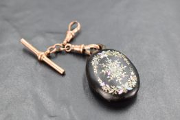 A 9ct rose gold T bar with clasp holding a jet fob having carved and inset mother of pearl