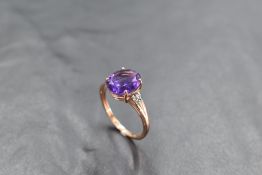 An oval heat treated amethyst ring having diamond chips to open shoulders on a 9ct rose gold loop,