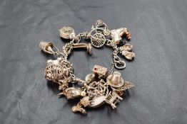 A silver and white metal charm bracelet, the chain with heart shaped padlock clasp and numerous