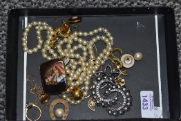 A small selection of costume jewellery incluing string of simulated pearls, ceramic pictorial