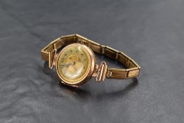 A lady's vintage 9ct rose gold wrist watch having Arabic numeral dial to decorative face with rolled