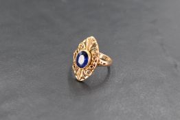 A yellow metal (thought to be gold) and blue stone dress ring, the central oval cut blue stone, most