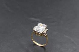 A large emerald cut cubic zirconia ring having cubic zirconia set shoulders on a 14ct gold loop,