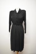 A 1940s Art Deco day dress in black having textured swirled panels to bodice and self covered
