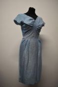 A 1950s Blanes dress in powder blue with metallic thread, having half belt to waist and simple,