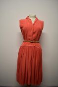 A 1950s coral pink cotton day dress having contrasting piping to collar, cuffs and waistline, side