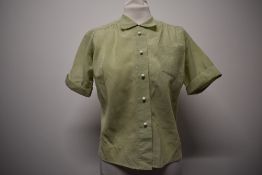 A 1950s mint green striped blouse, having 3/4 sleeves and spherical white buttons.
