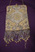 An Art Deco metallic beaded evening bag having gold tone fame and clasp fastening with blue gem