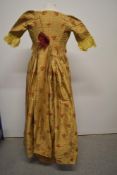 A 19th century gold dress with embroidered floral sprigs, having open skirt, train to back, hook and