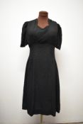 A 1940s black textured day dress, having sweetheart neckline and self covered buttons to reverse.