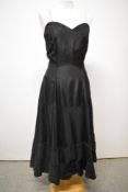 A 1940s black under slip having fairly full tiered skirt with stiffened hem and side metal zip.