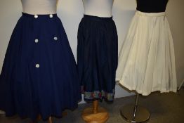 Three 1940s to 1950s vintage skirts, including blue cotton with pleated hem and white buttons to