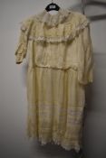 An Edwardian child's dress of cream silk and lace, with pin tucks to hem and smocked sleeves.