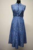 A blue taffeta day dress having floral pattern, button and fabric loop fastening to front and side
