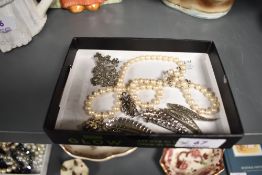 A vintage pearl or simulated necklace, four metal brooches and a set of clip on earrings.