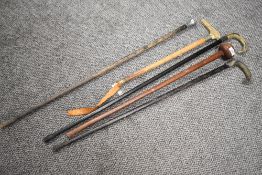 Three vintage walking sticks including horn handled, a riding crop and a hard wood club.