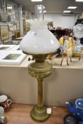 A Victorian oil burning lamp with a brass Roman style column base with milk glass light shade.