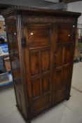 A Period style oak hallrobe having panelled doors and sides , with lunette carved decoration over