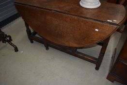 A traditional oak heavy gateleg dining table, width approx. 135cm, having circular design to centre