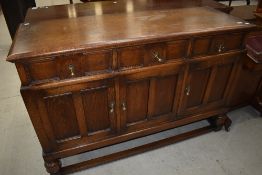 A 1940's oak sideboard, having three frieze drawers and panelled cupboards, on short turned legs