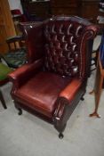 A modern oxblood leather wingback armchair having button back