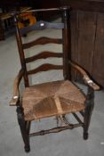 A 19th Century ladder back chair in the Macclesfield style having rush seat (af)