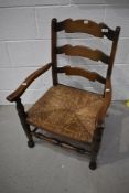 A nursing chair having oak frame with rush seat and ladder back