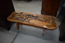 A traditional golden oak coffee table having carved ploughing decoration, width approx. 111cm
