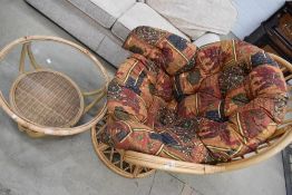 A wicker easy chair and similar glass top occasional table