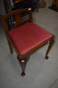 An early 20th Century piano or dressing table stool with dralon seat and cabriole legs