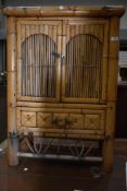 A traditional oriental style bamboo side cabinet having brass handles and cushion drawer