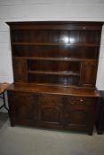 A traditional oak dresser having delft rack base with double panelled cupboard and triple drawer and