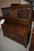 A Priory style oak dresser having glazed display section over triple drawer and cupboard base, width