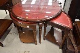 A reproduction coffee table , with quadruple nest below, all having red skiver tops and classical