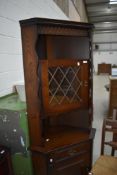 A reproduction oak effect corner display with cupboard base
