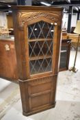 A mid to late 20th Century oak corner display having cupboard under, in the Priory style