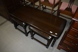 A dark stained Ercol style coffee table having two smaller tables nesting beneath, approx 114 x