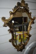 A gilt effect mirror of foliate scroll design