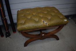 A reproduction Savanorola style stool having worn leather button seat