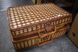 A traditional picnic basket housing a collection of plastic plates and bowl.
