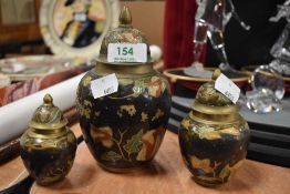 Three graduated lidded brass urns, having enamel detailing.