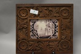 A 19th century Delft tile having Chinoiserie design in purple to white ground, mounted in carved oak