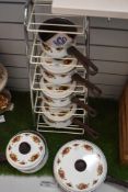 A stand housing a variety of pans having rose pattern to white enamel, comprising; frying pan and
