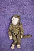 A mid 20th century straw filled and brown plush jointed monkey having felt hands and feet