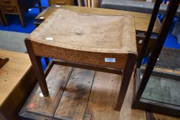 An Arts and Crafts golden oak stool having plain leather seat, believed to be Arthur Simpson
