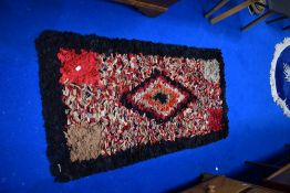 A pegged rag rug, black, red and cream tones, approx. 130 x 70 cm