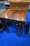 A reproduction walnut nest of three tables